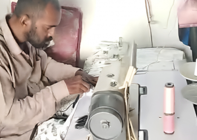 Man using sewing machine to create clothing and earn wages
